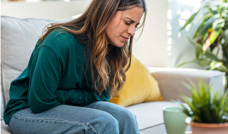 A woman bends over in pain, holding her stomach